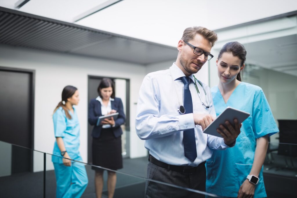 People reviewing information on a tablet with nurses, representing collaboration, patient care, and healthcare technology use