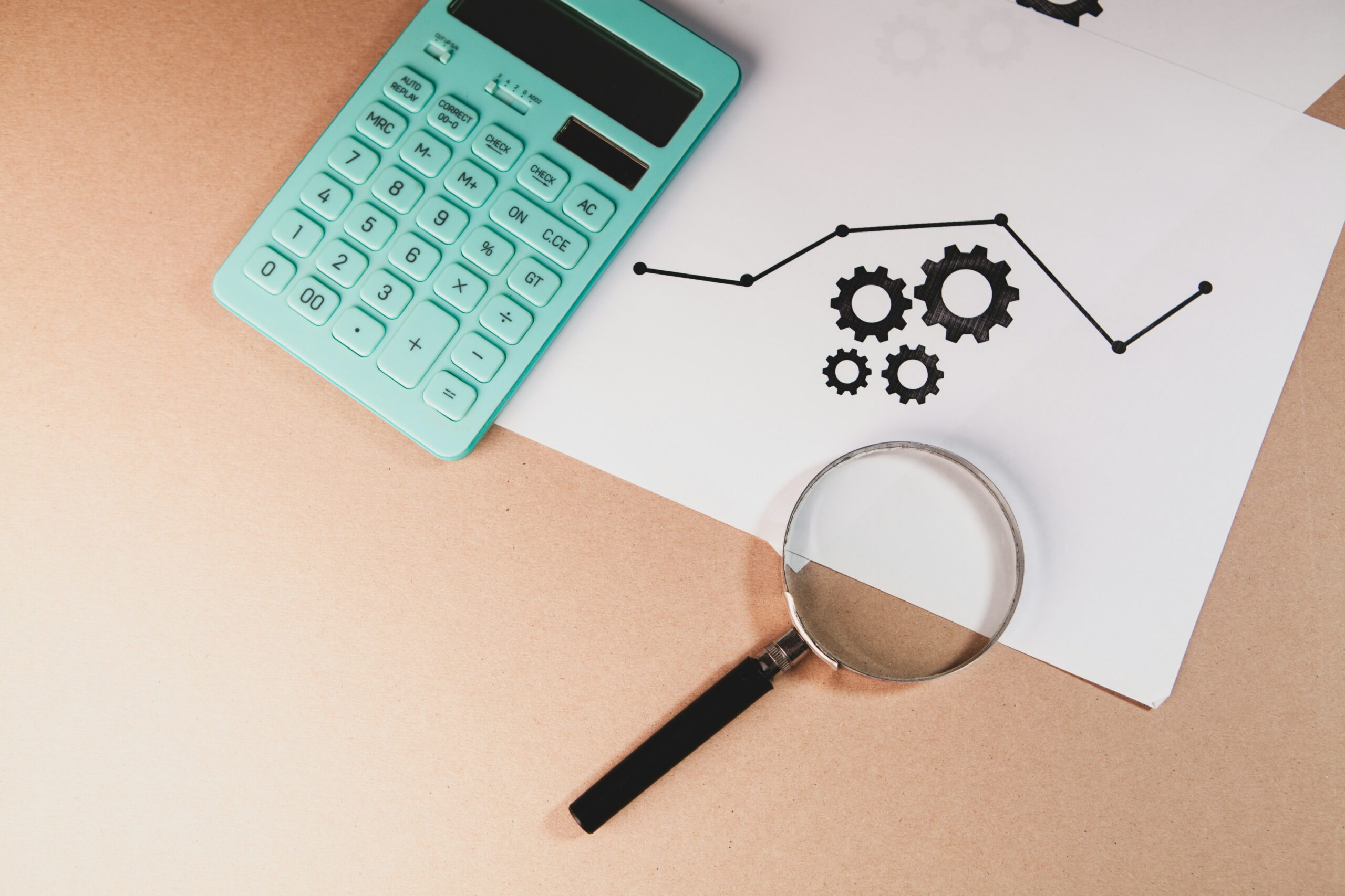 Calculator and magnifying glass on a document with gear icons representing IT cost analysis and operational optimization.