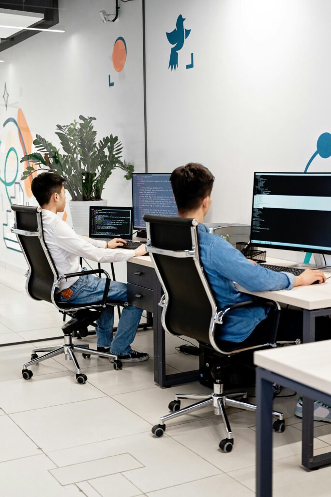 Developers collaborating on coding projects at computers, representing software engineering and IT problem-solving.