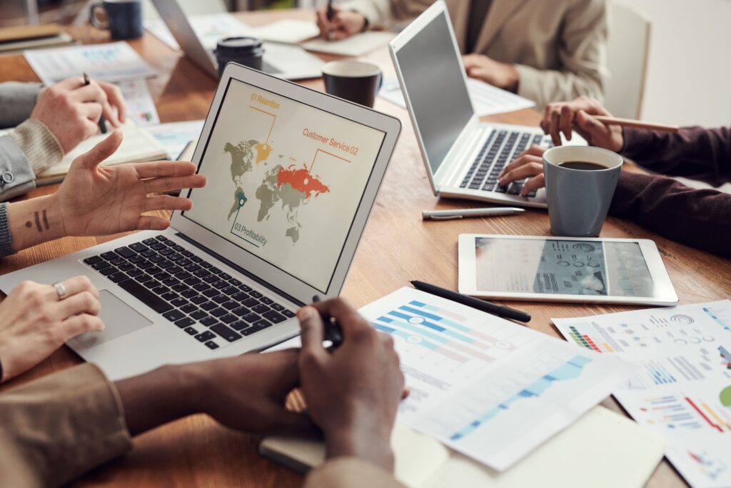 Team reviewing a world map on a computer during a meeting, representing global operations and strategic planning.